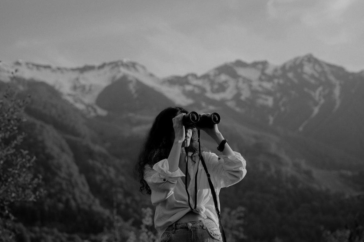 A person scanning a mountain range through binoculars